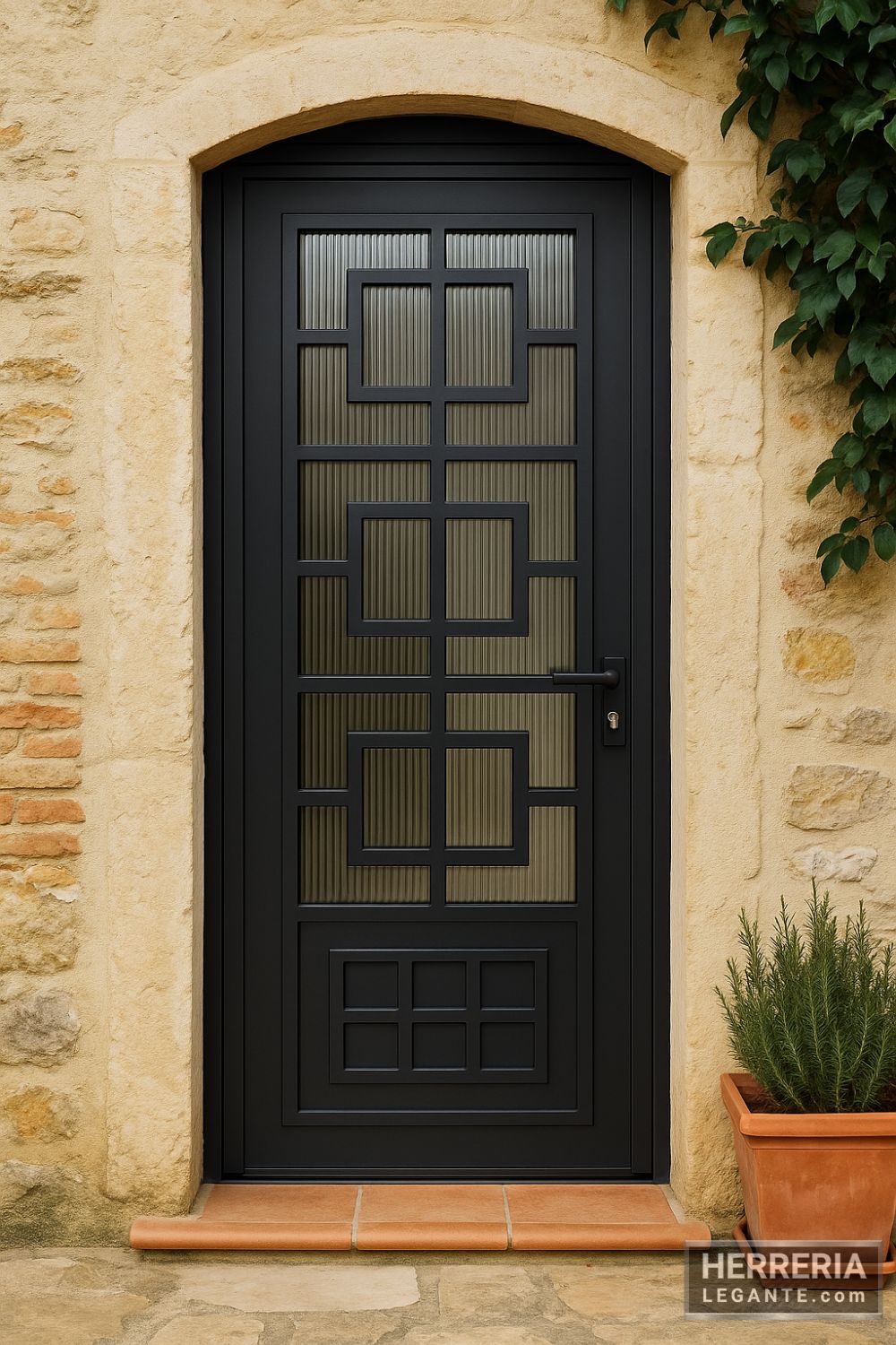 Puerta de herrería negra con vidrio estriado y patrón de cuadros simétricos instalada en fachada rústica con piedra expuesta y maceta de terracota