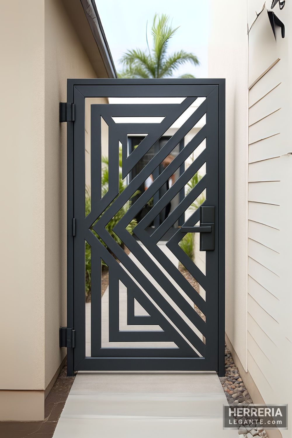 Puerta de herrería con diseño geométrico diagonal vista desde el pasillo lateral de una casa moderna