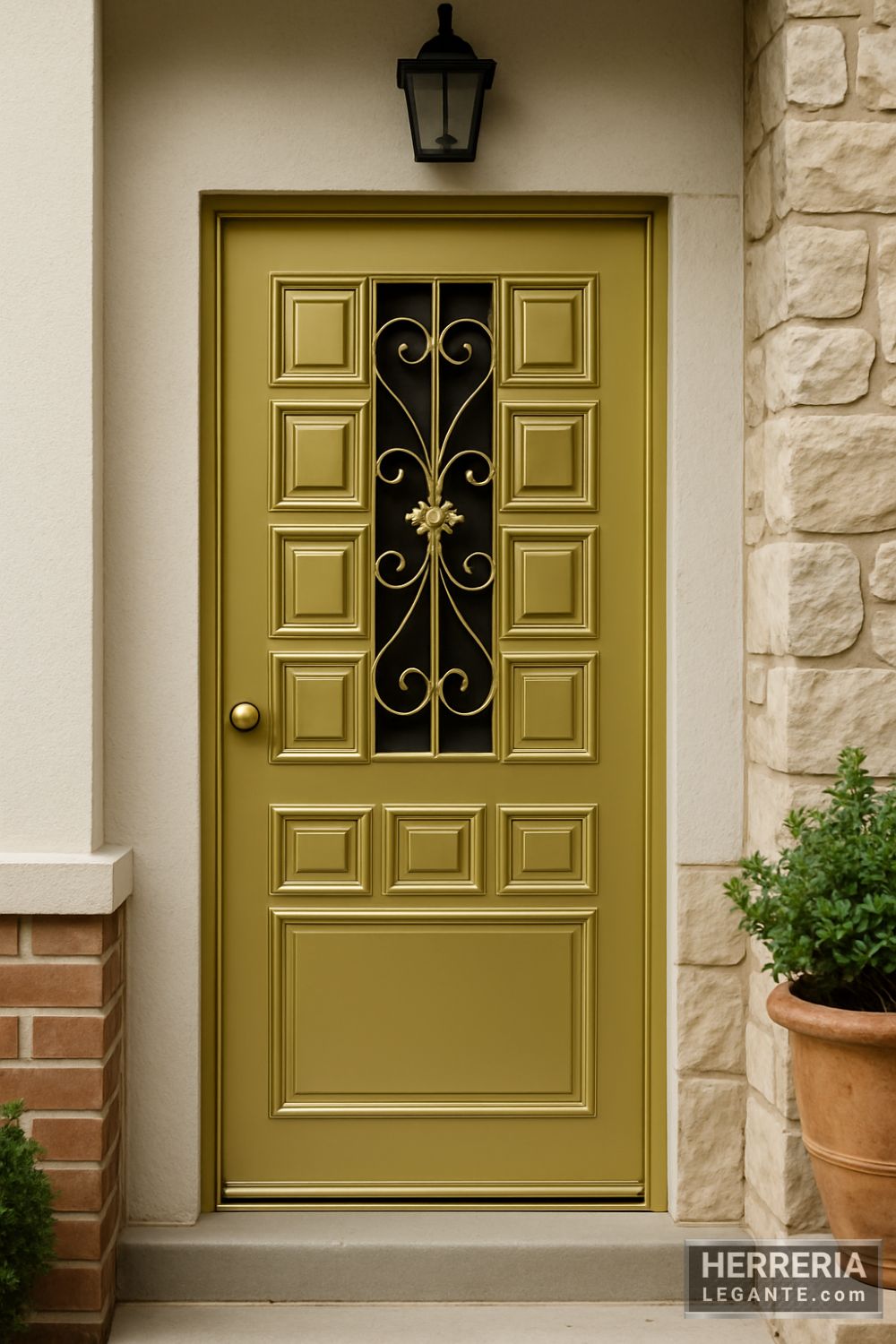Puerta de herrería clásica en acabado dorado satinado con paneles geométricos y enrejado decorativo, instalada en fachada de casa tradicional con muros de piedra y estuco