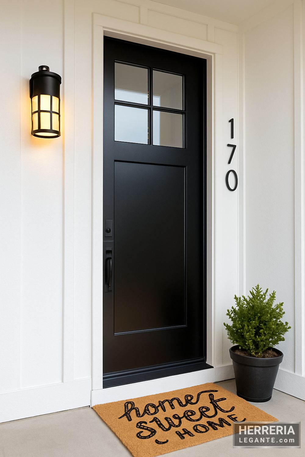 puerta de herrería negra con cuatro vidrios superiores y panel inferior, instalada en fachada remodelada estilo farmhouse con colores claros